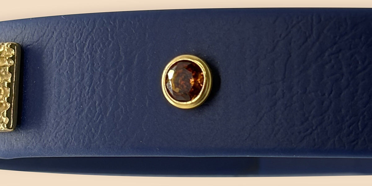 Dettaglio del cristallo ambra con ghiera dorata sul blu navy