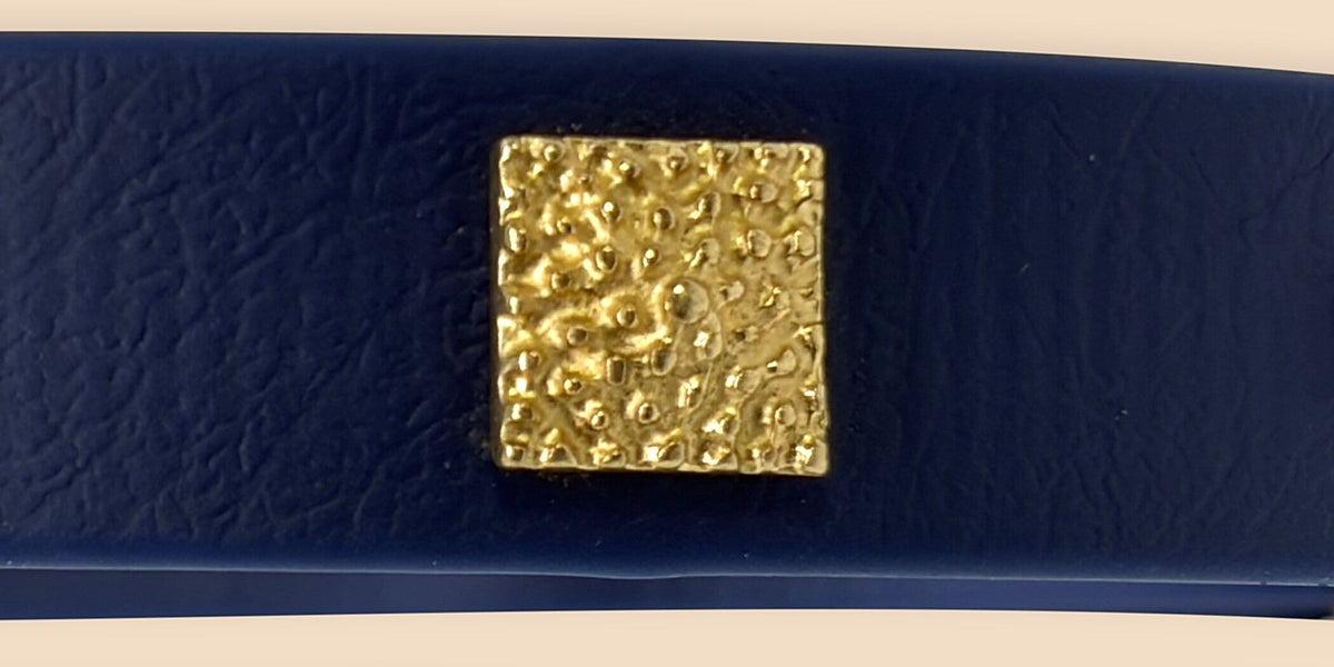 Dettaglio della borchia quadrata dorata sul blu navy